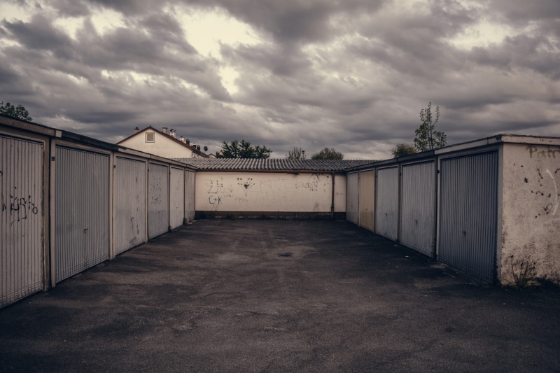 lot, built structure, gate, garage door, wall, garage, no people, overcast, direction, closed, cloud - sky, entrance, building, building exterior, parking