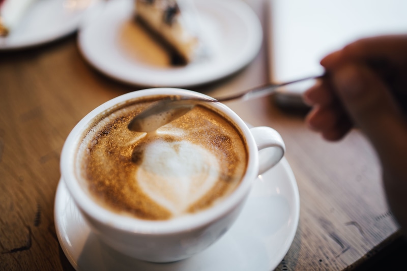 latte, frothy drink, hot drink, coffee - drink, human hand, coffee break, crockery, human body part, table, mug, indoor, close-up, cappuccino, coffee, coffee shop