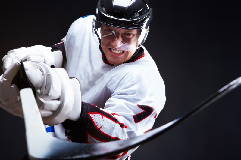 three quarter length, athlete, front view, hockey stick, smiling, stick, white, speed, adult, black background, looking at camera, competitive Sport, mouth open