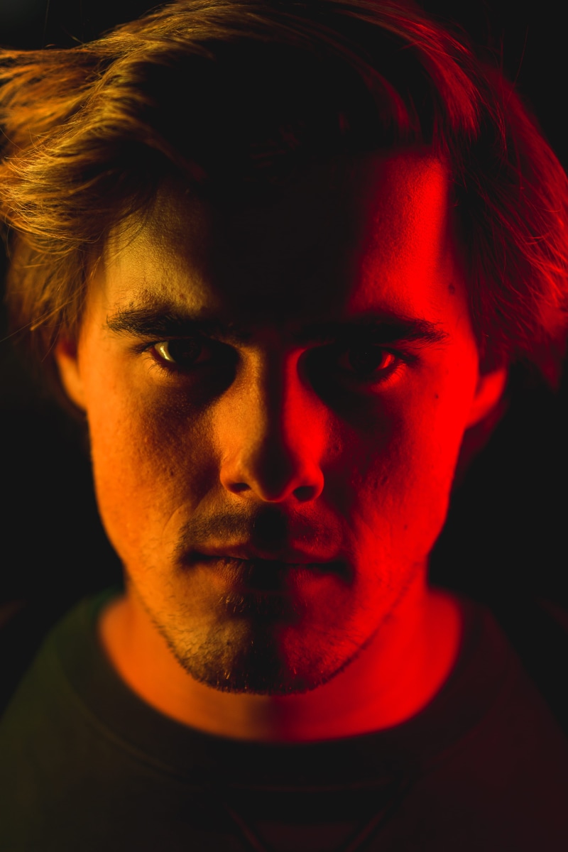 dark, one person, black background, neck, adult, ring light, nanguang, 5K, hairstyle, studio, indoors, studio shot, young adult, black, human face, red