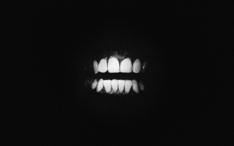 one person, music, human body part, domestic room, black background, Swans, album covers, low angle view, body part, teeth, illuminated, lighting equipment