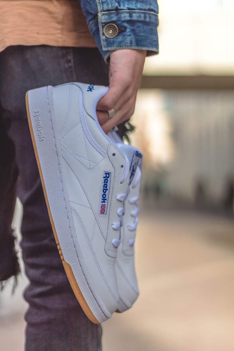 sleeve, human, shoe, holding, midsection, long sleeve, human hand, white shoes, antwerp, feetwear, real people, adult, sneakers, shoes, running shoe, low