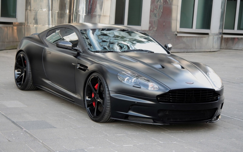 vehicle, car, gray, land vehicle, black cars, outdoors, garage, city, built structure, vintage car, coupe, day, street, architecture, Aston Martin, no people