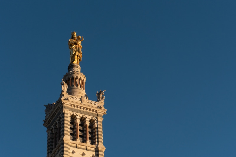 skyscraper, building exterior, clear sky, spire, tower, france, eye, clock tower, brown, sculpture, art and craft, architecture, statue, marseille, built structure