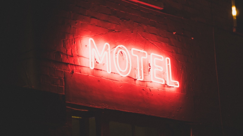 illuminated, red, indoors, capital letter, western script, built structure, text, motel, lighted, light, lights, lighting equipment, commercial sign, glowing