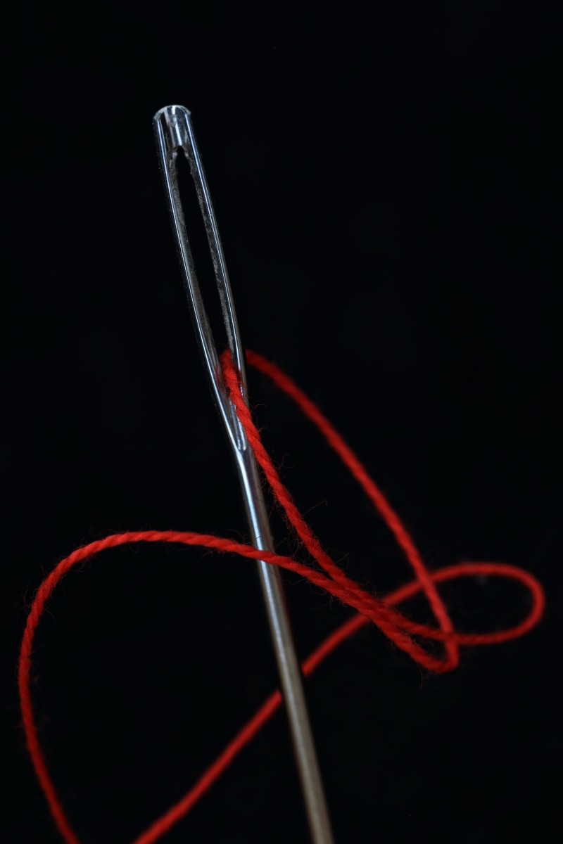 two objects, needle, yarn, simplicity, colored background, haberdashery, 5K, indoors, black background, fabric, thread, studio shot, handarbeiten, intertwined