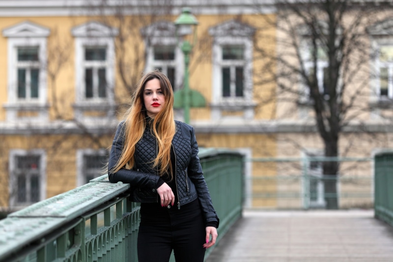 long hair, standing, architecture, built structure, leather, depth of field, leather jacket, lifestyles, looking at camera, model, city, building exterior