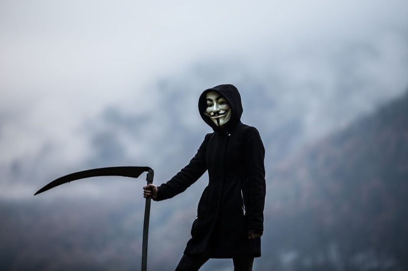 one person, photoshoot, male likeness, low angle view, day, wearing, nature, mask, photo, statue, creepy, holding, hoodie, three quarter length, sculpture