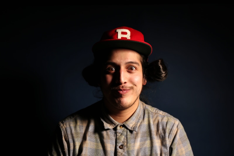 dark, photoshoot, face, baseball cap, indoors, black background, lighting, fitted, light, gray, man, dude, studio shot, eyes, smile, one person, happiness