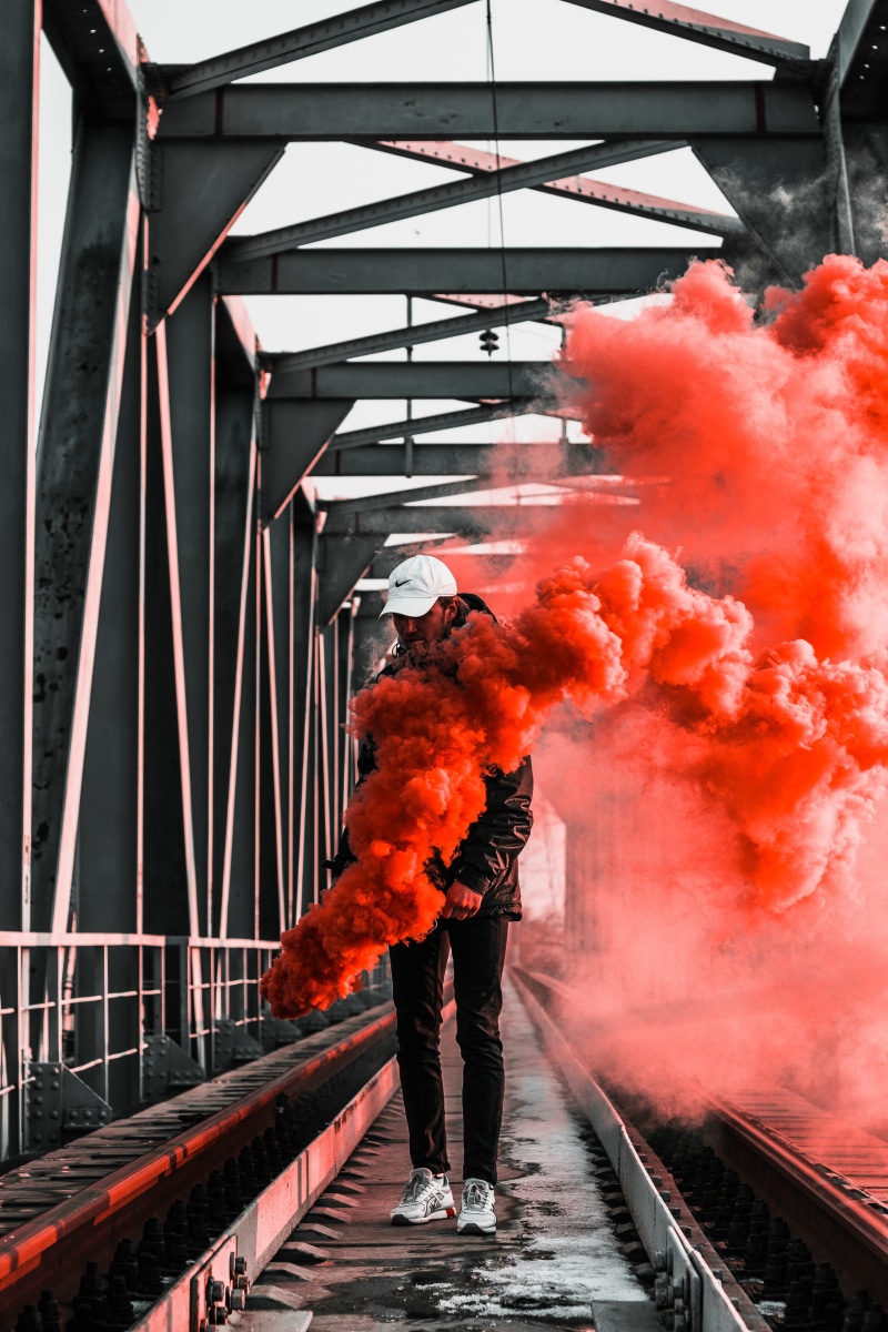 smoke - physical structure, holding, metal, railway, nature, day, fire - natural phenomenon, orange color, smoke bomb, fire, motion, full length, person