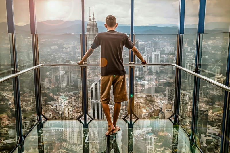 man, building exterior, glass - material, casual clothing, glass items, indoors, reflection, black, looking, lifestyles, standing, sunlight, buildings