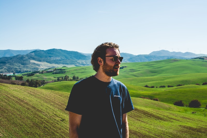 plant, young adult, crew, man, beauty in nature, neck, casual clothing, male, young men, sunlight, black, landscape, nature, hills, grass, wearing, one person