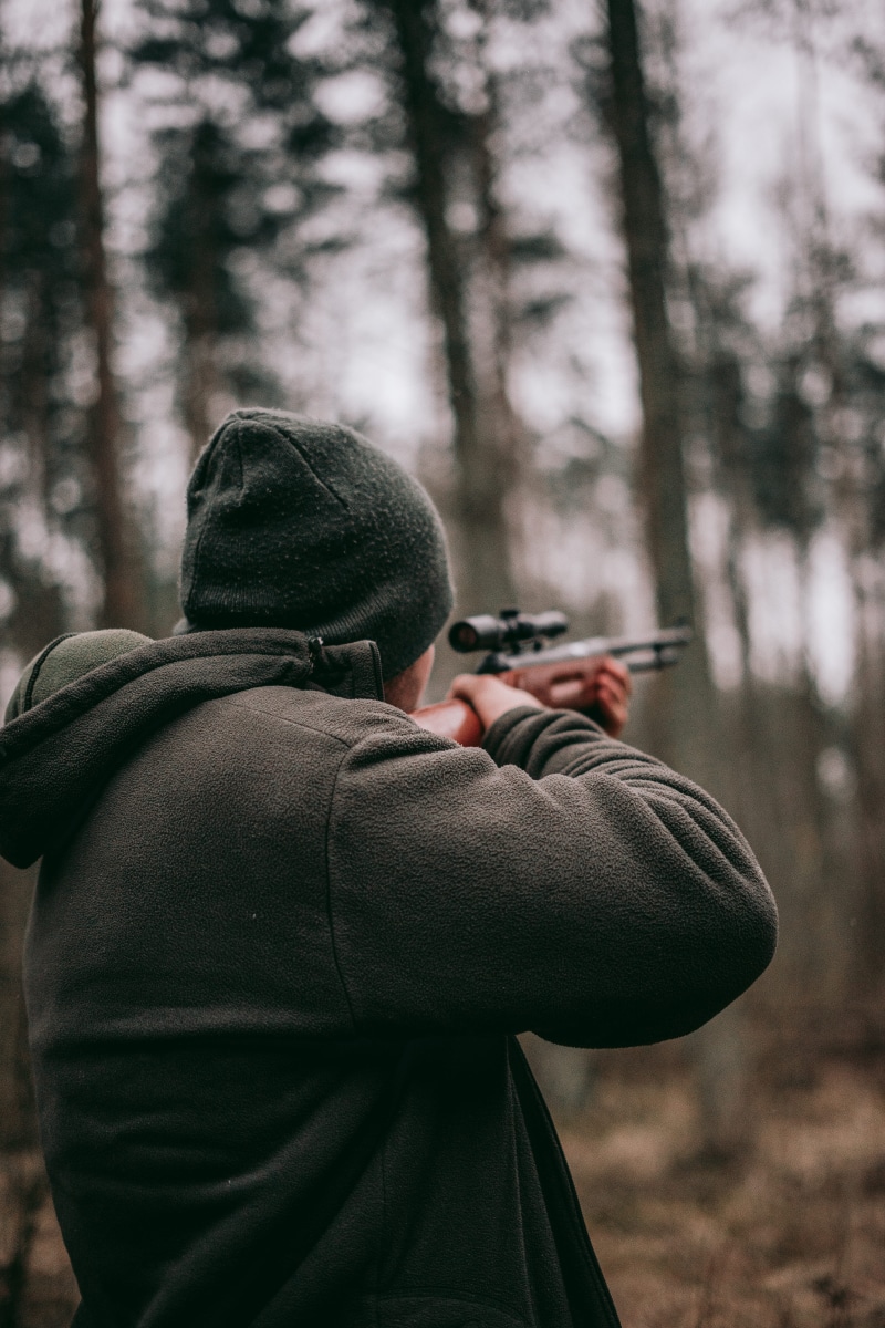 hoodie, real people, leisure activity, warm clothing, forest, hunting, sniper, people, clothing, lifestyles, photographing, one person, depth of field