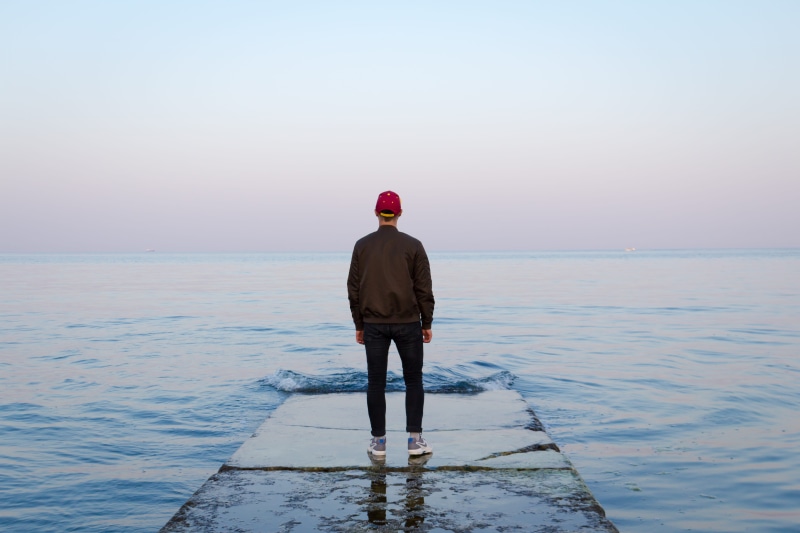 water, adult, rear view, facing, floading, male, dock, person, solitude, looking at view, pier, brown, beach, body, looking out at the horizon, horizon over water