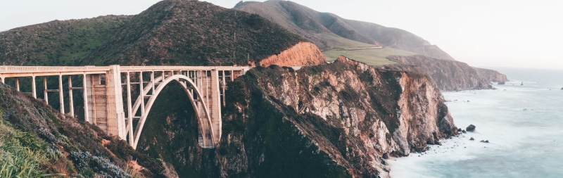 dusk, arch bridge, land, built structure, sea, sunset, famous, vacation, transportation, calm, outdoors, fog, water, sky, dawn, mountain, architecture