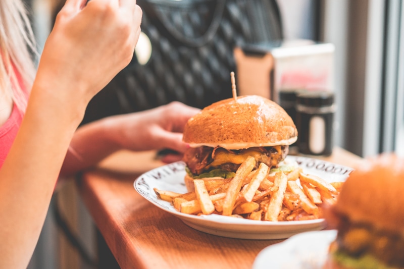meal, table, take out food, sandwich, prepared potato, freshness, hamburger, human hand, indoors, food and drink, burger, one person, close-up, potato