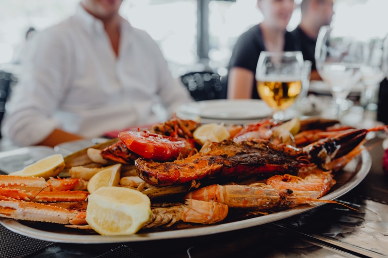 restaurant, meat, lunch, drink, two people, men, glass, see, contain, meal, tray, mixed, dinner, dining, food, plate, big, dish, prawn, focus on foreground