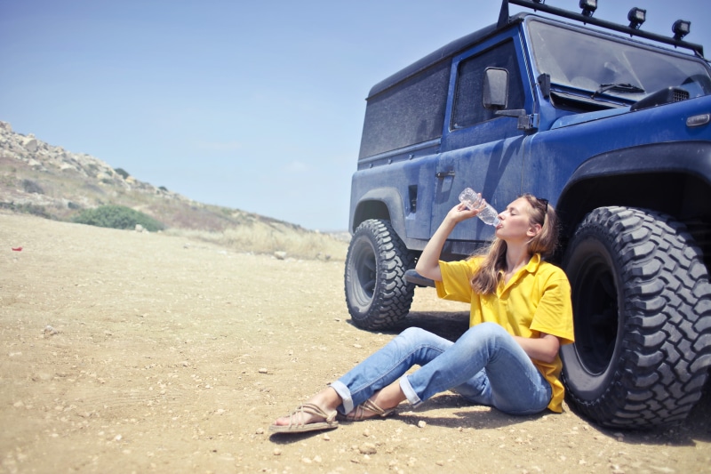slippers, yellow, yellow polo shirt, outside, blue jeans, girl, shirt, yellow shirt, day, landscape, sky, woman, off road, drink, sunglasses, black sunglasses