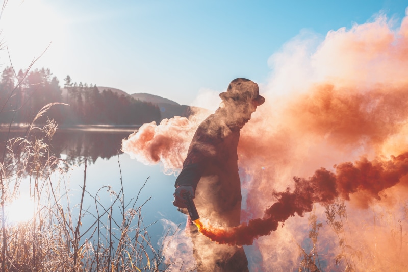sky, smoke - physical structure, nature, water, bomb, flare, beauty in nature, near, lens flare, holding, daytime, sunbeam, man, male, fire - natural phenomenon
