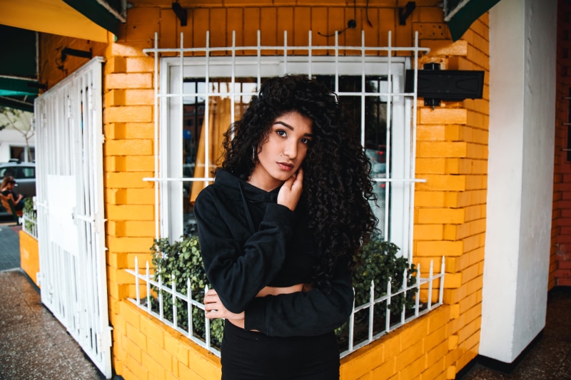smiling, outdoors, young Women, adult, pullover, young Adult, city, pose, door, caucasian Ethnicity, female, beauty, wall, curly hair, latin American and Hispanic Ethnicity