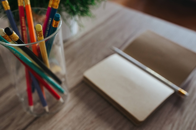 writing instrument, box - container, easel, paintbrush, art and craft, writing, indoors, colourful, journal, high angle view, art, notebook, table, pencils