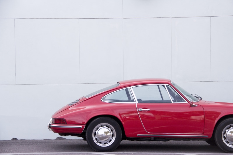 retro styled, outdoors, asphalt, coupe, vintage car, single object, wall, city, vintage, near, parked, red, white, built structure, motor vehicle, mode of transportation