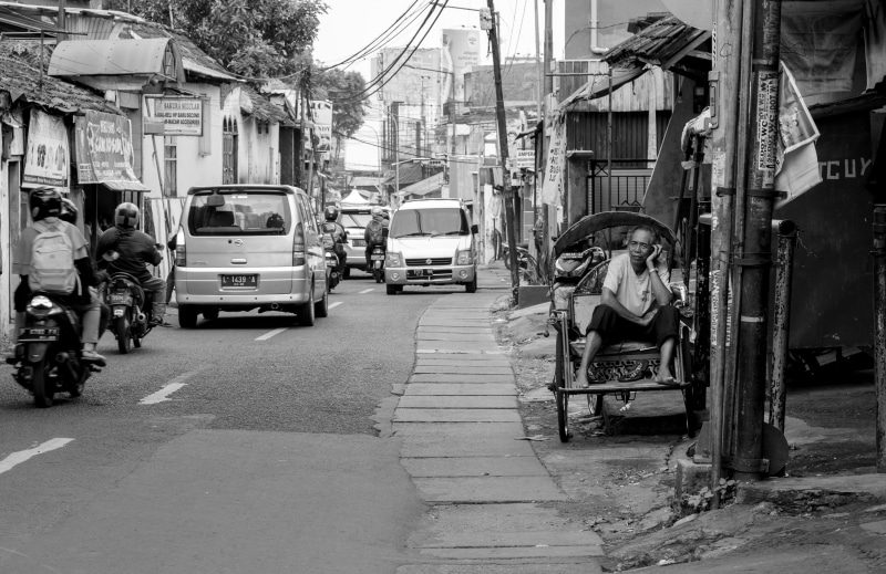outdoors, grayscale, urban, city, one person, building, motorcycle, real people, day, town, furniture, neighborhood, near, architecture, land vehicle, photography