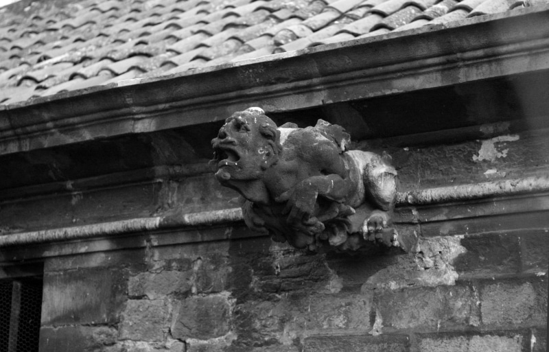 low angle view, the past, outdoors, deforme, dirty stone, sculpture, palacio antiguo, building exterior, gargoyle, no people, hombre, focus on foreground