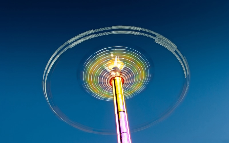theme parks, clear sky, traveling carnival, amusement park ride, 2K, blue background, nightlife, carnival, no people, night, circle, blurred motion, speed