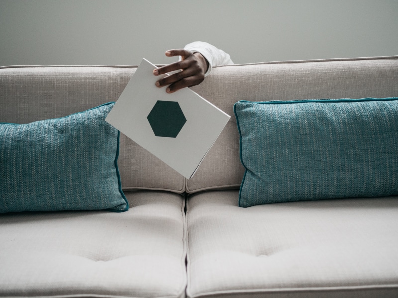 adult, one person, home interior, book, human body part, shape, geometric, domestic room, domestic life, african american, furniture, print, card, hiding