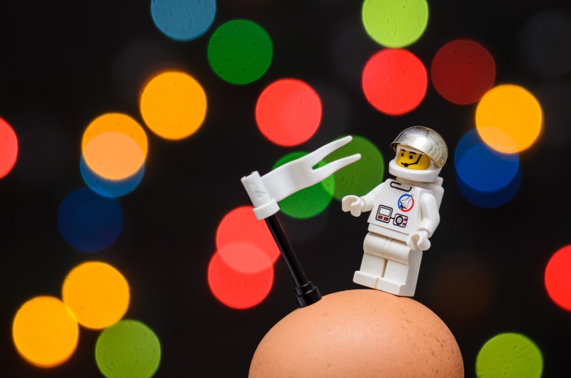 indoors, toys, human body part, astronaut, human limb, close-up, one person, illuminated, fantasy, conquest, space, spaceman, black background, holding