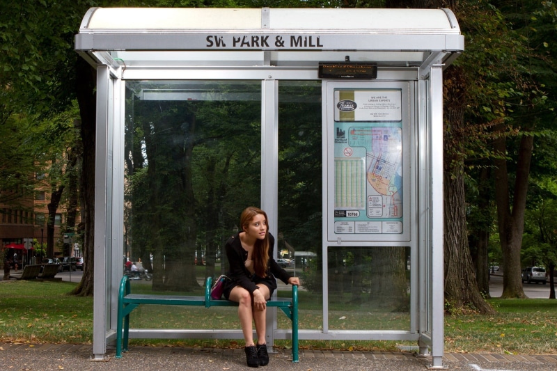 local, hairstyle, communication, bus stop, building exterior, waiting, architecture, outfit, leisure activity, only women, shoes, public transport, one person