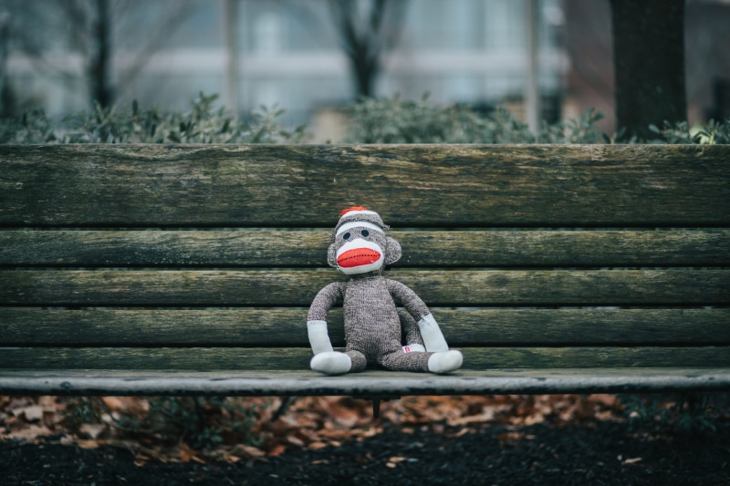 clothing, art and craft, monkey, handrail, figurine, shelf, human representation, sitting, wood, playground, dirt road, sock, representation, bench, toy