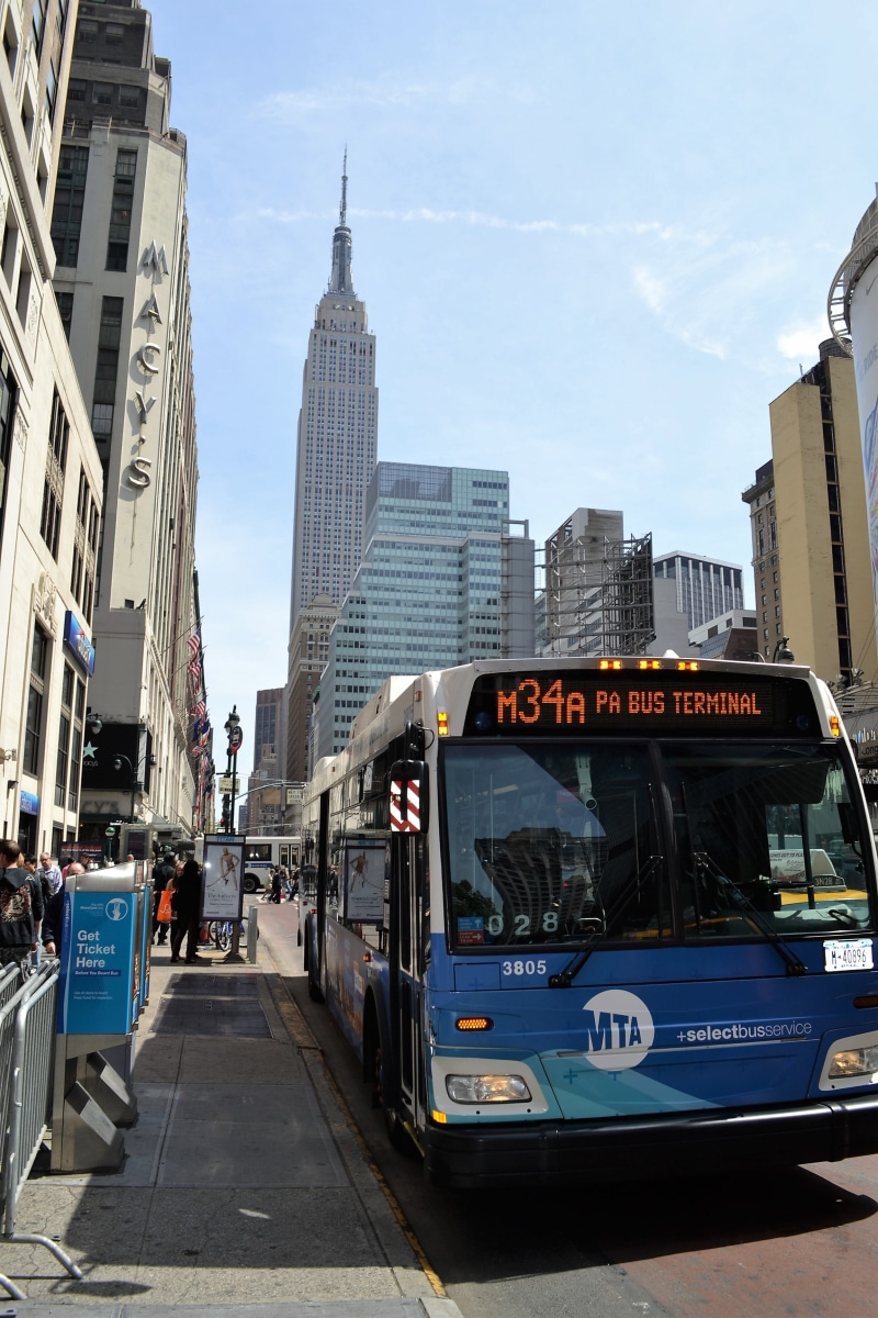 western script, building, motor vehicle, t, metro, outdoors, building exterior, blue bus, monument, text, manhattan, city, land vehicle, public transportation