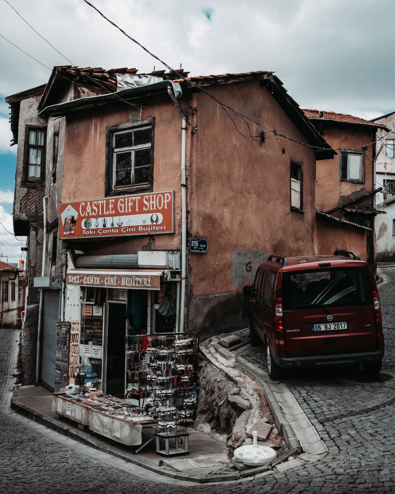 communication, mode of transportation, building exterior, text, roof, urban, car, street, gift shop, tire, automobile, ankara, walkway, land vehicle, western script