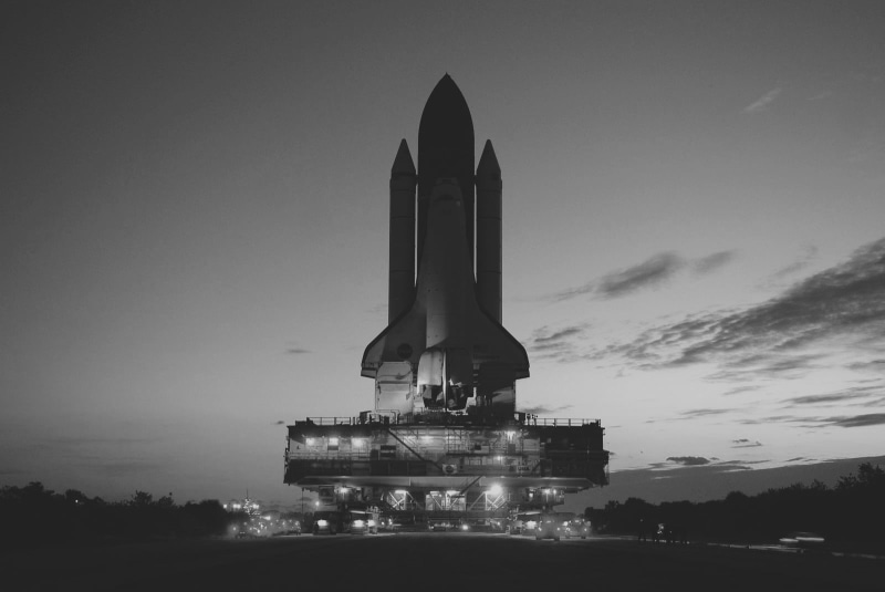 spaceship, building exterior, tree, rocket, outdoors, nature, space rocket, monochrome, mode of transportation, night, technology, cloud - sky, tall - high