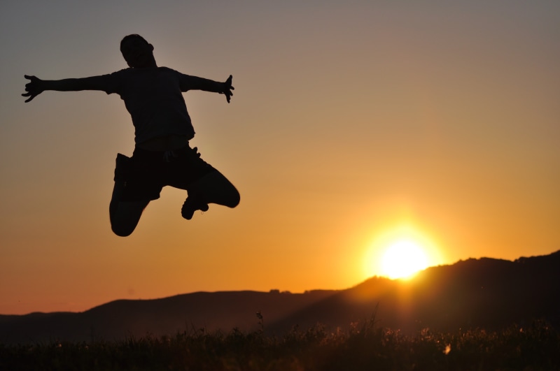 limb, nature, jumping, hills, outdoors, sky, mid-air, scenics - nature, orange color, human arm, grass, sunlight, arms raised, one person, beauty in nature