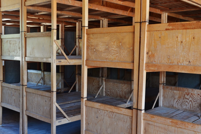 bad, 2 floors, indoors, built structure, brown, past, bunkhouse, construction site, death, furniture, history, ceiling, roof beam, wood - material, day