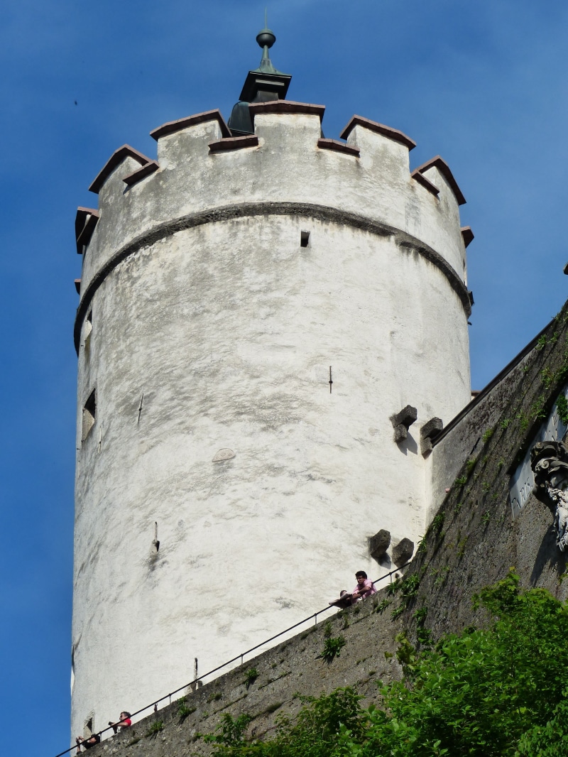 clear sky, outdoors, low angle view, built structure, leisure activity, fort, defensive tower, imposing, blue, people, landmark, enormous, tower, tourist attraction