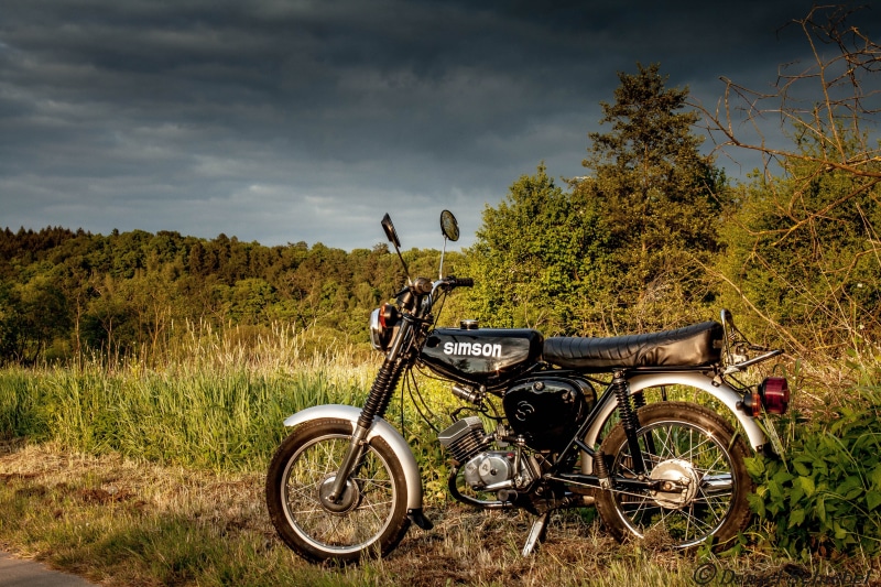plant, land vehicle, on the go, day, outdoors, nature, green color, clouds, landscape, cloud - sky, no people, field, stationary, moped, dom, bike, land