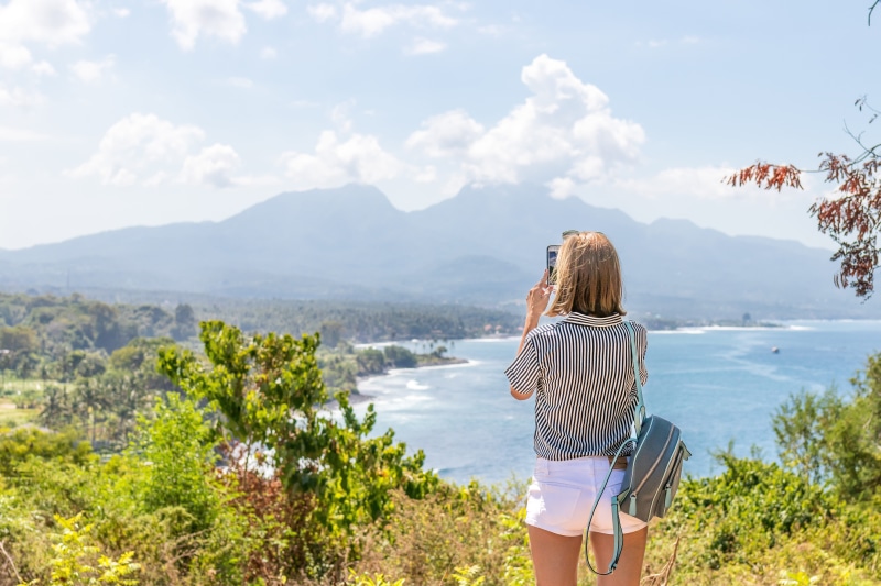 casual clothing, mountain, cliff, beautiful, sea, forest, water, lifestyle, short, peak, standing, taking photo, happy, taking picture, view, looking at view