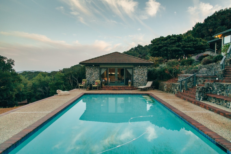 behind, mountain, poolside, day, building, outdoors, tree, reflection, no people, tourist resort, mountains, building exterior, luxury, water, 2K, built structure