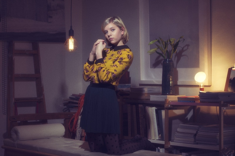 sitting, home interior, chair, real people, illuminated, front view, candle, standing, beautiful woman, musician, 720P, Aurora Aksnes, lighting equipment
