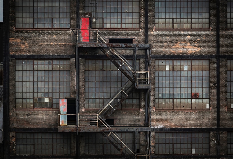 low angle view, architecture, window, outdoors, broken windows, railing, factory, bullet holes, safety, wall, built structure, no people, destruction, brick