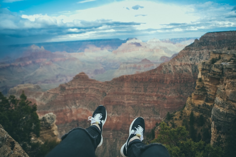 scenics - nature, hiking, real people, feet, lifestyles, leisure activity, cloud - sky, one person, canyon, low section, shoes, extreme Terrain, cliff
