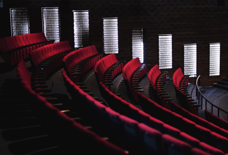 indoors, equipment, lights, arm rest, comfort, chair, side by side, auditorium, movie theater, number, interior, in a row, music, red, event, large group of objects