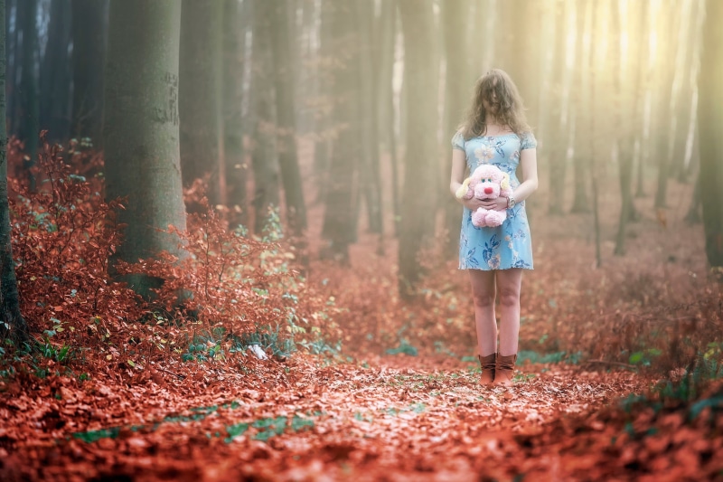 smiling, stuffed animal, brown, dress, outdoors, females, plant part, love, hairstyle, forest, tree, hair, forest clearing, woman, casual clothing, mother