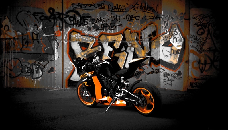 text, motorcycle, mural, graffiti, black, mode of transportation, land vehicle, rc8 r, 2K, no people, city, bike, art and craft, garage, orange, ktm, indoors