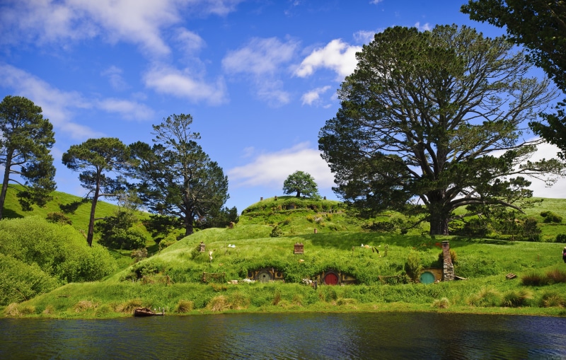 non-urban scene, beauty in nature, outdoors, lake, plant, tranquil scene, cloud - sky, tree, land, nature, growth, scenics - nature, green color, hobbiton