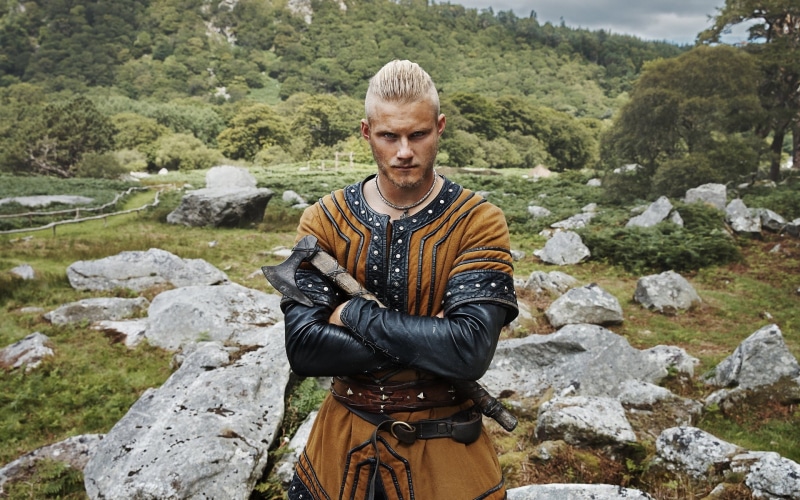 lifestyles, nature, young adult, casual clothing, river, hiking, solid, real people, rock, leisure activity, water, men bjrn ironside alexander ludwig blonde actor tv vikings tv series axes traditional clothing